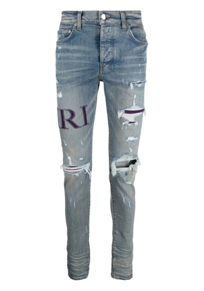 AMIRI ripped-knee logo-print skinny jeans - Blue