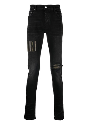 AMIRI logo-appliqué distressed jeans - Black